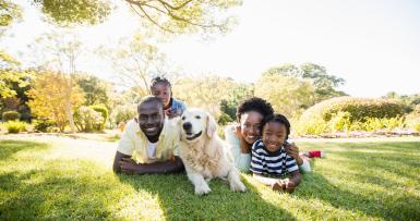 family of four and dog laying on grass outside
